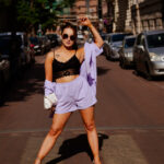 Sesja kobieca w mieście – modelka w liliowym komplecie i okularach, pewna poza na ulicy, letnie słońce, Łódź